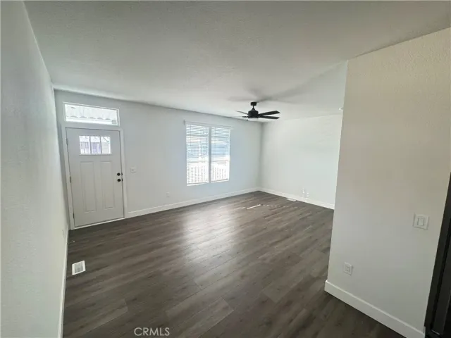 an empty room with wooden floor cabinet and windows
