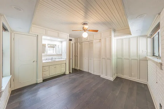 an empty room with wooden floor closet and windows