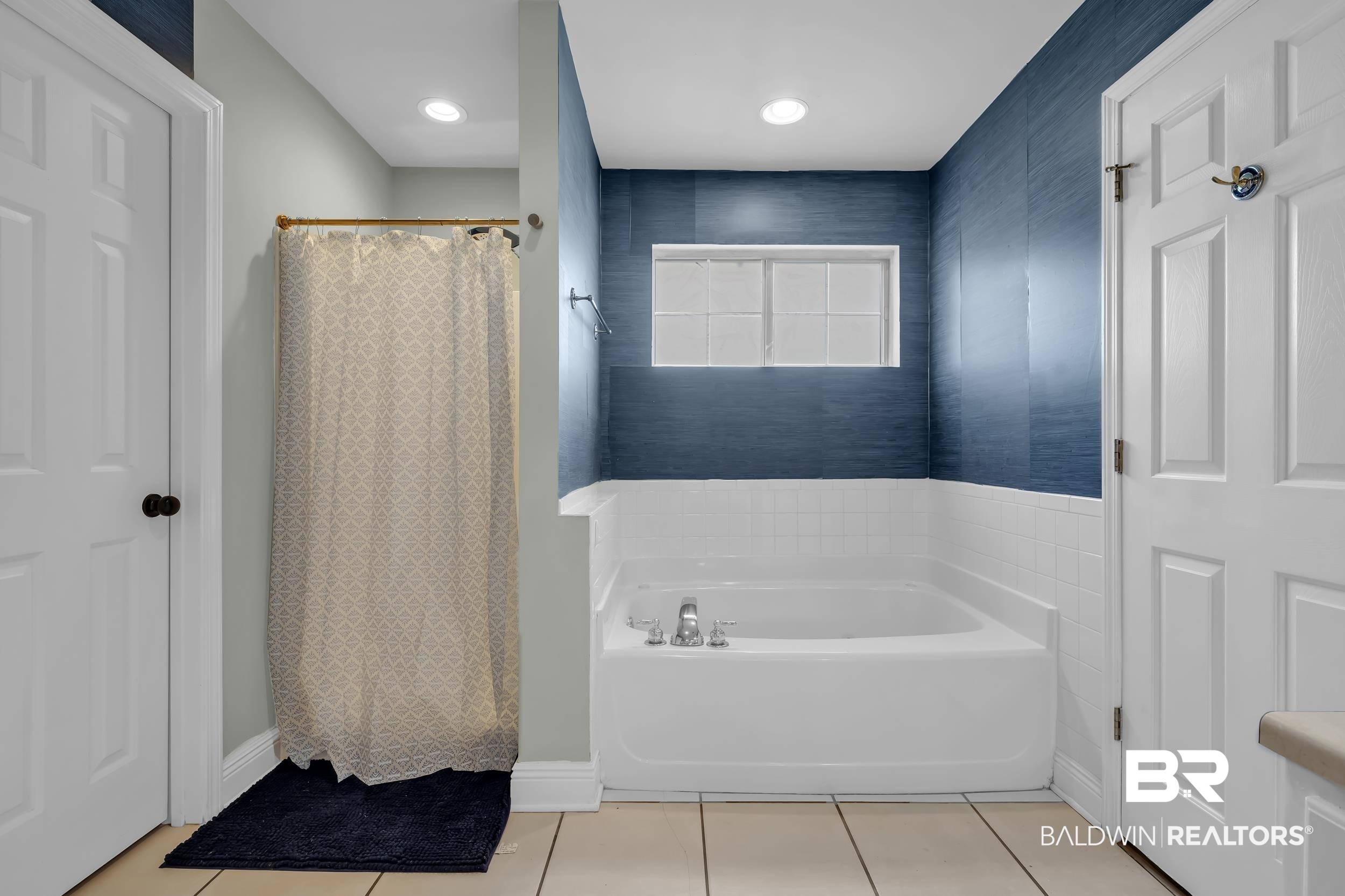 509 Loblolly Court Foley, AL 36535 - Photo 16 of 26 Built-in tub with a tiled surround, complemented by textured blue wallcovering and a transom window