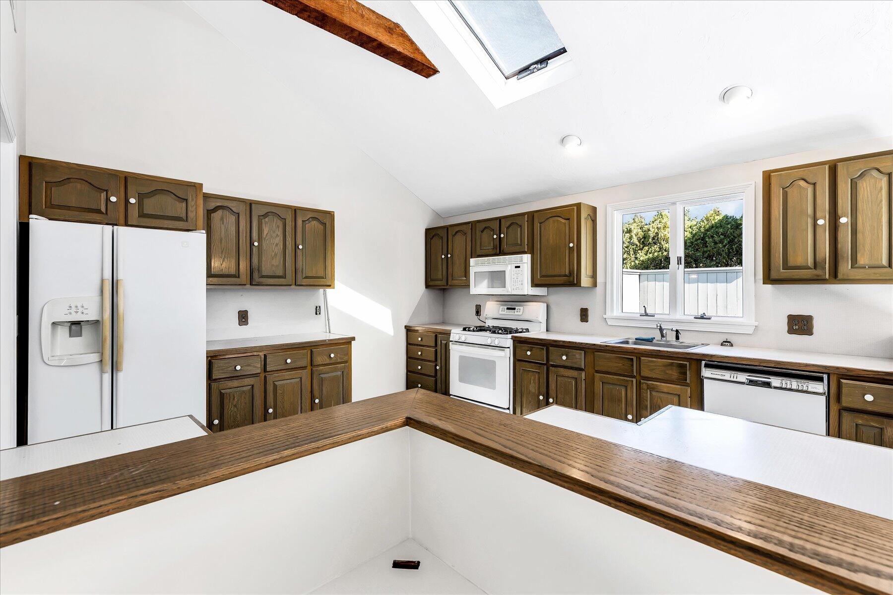 19 Mashnee Road Bourne, MA 02532 - Photo 15 of 46 a large kitchen with a refrigerator a stove top oven a sink a dishwasher with wooden cabinets and floor