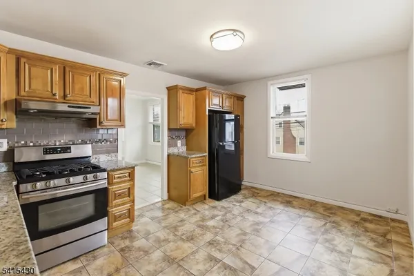 a kitchen with stainless steel appliances granite countertop a stove a refrigerator and a cabinets