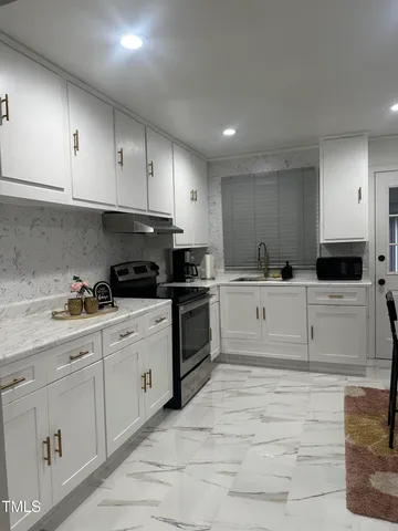 a kitchen with granite countertop white cabinets and white appliances
