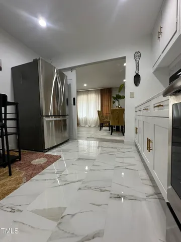 a view of a refrigerator in kitchen and an empty room
