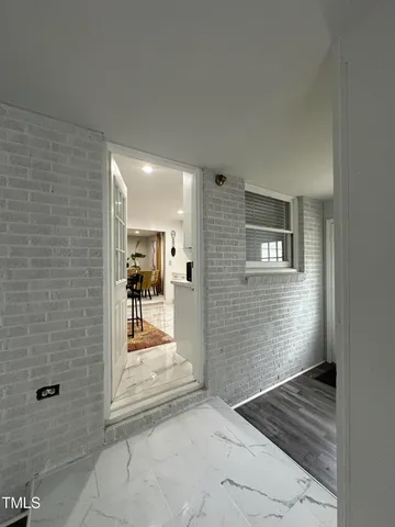 a view of a hallway with wooden floor and a bathroom