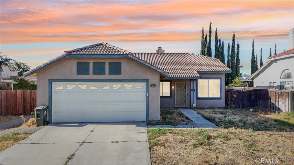 11565 Spring Street Adelanto, CA 92301 - Photo 1 of 1 a front view of a house with a yard and garage