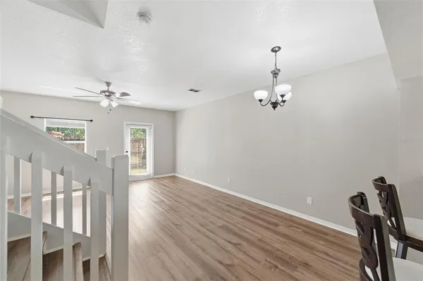 a view of a room with wooden floor chandelier fan and windows