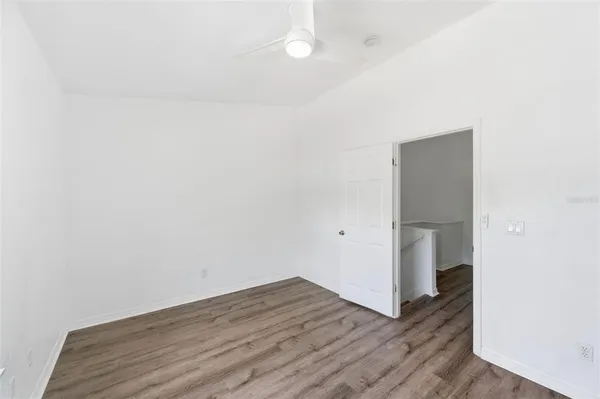 a view of an empty room with wooden floor and closet
