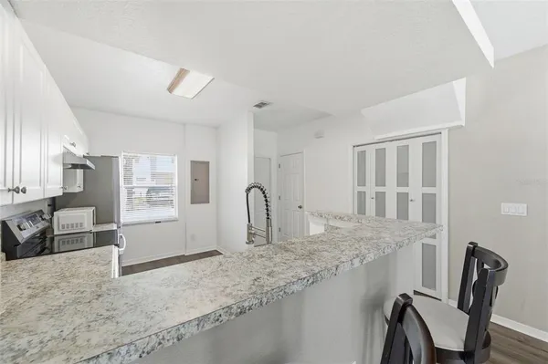 a kitchen with stainless steel appliances granite countertop a stove top oven a sink a dining table and chairs with wooden floor