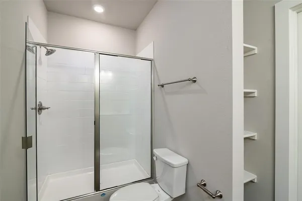 a bathroom with a shower a toilet and a glass door