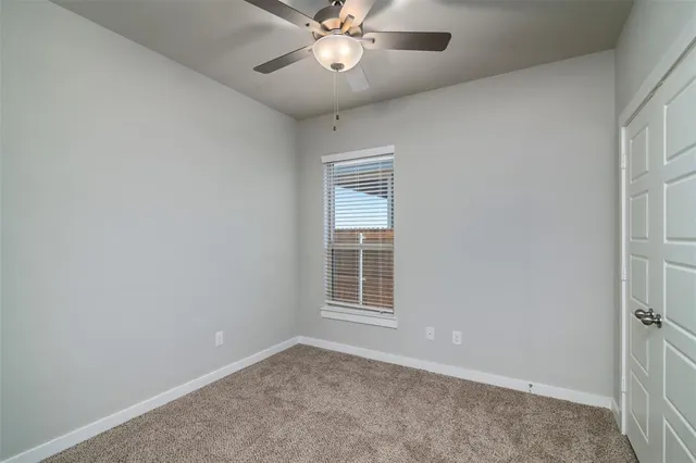 an empty room with a chandelier fan and windows