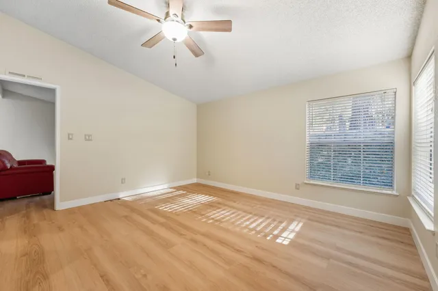 a view of an empty room with wooden floor and a window