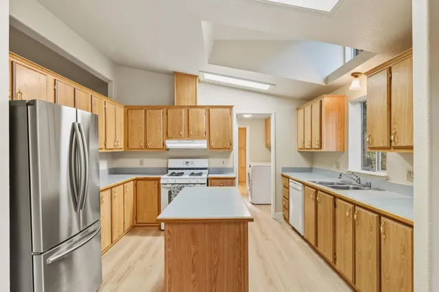 a kitchen with stainless steel appliances granite countertop a refrigerator a stove top oven a sink and dishwasher