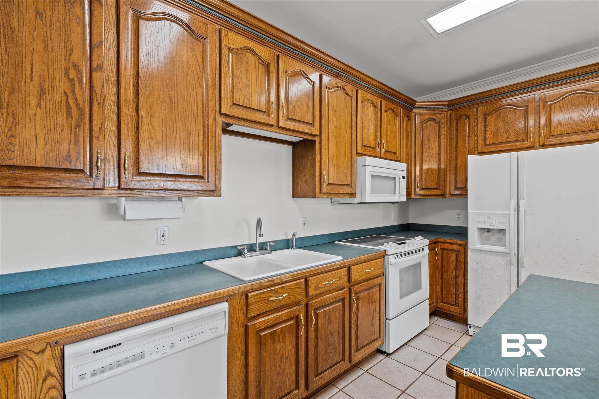 41923 Bayou Road Bay Minette, AL 36507 - Photo 10 of 35 Kitchen featuring wood cabinetry, blue countertops, white appliances, and tile flooring