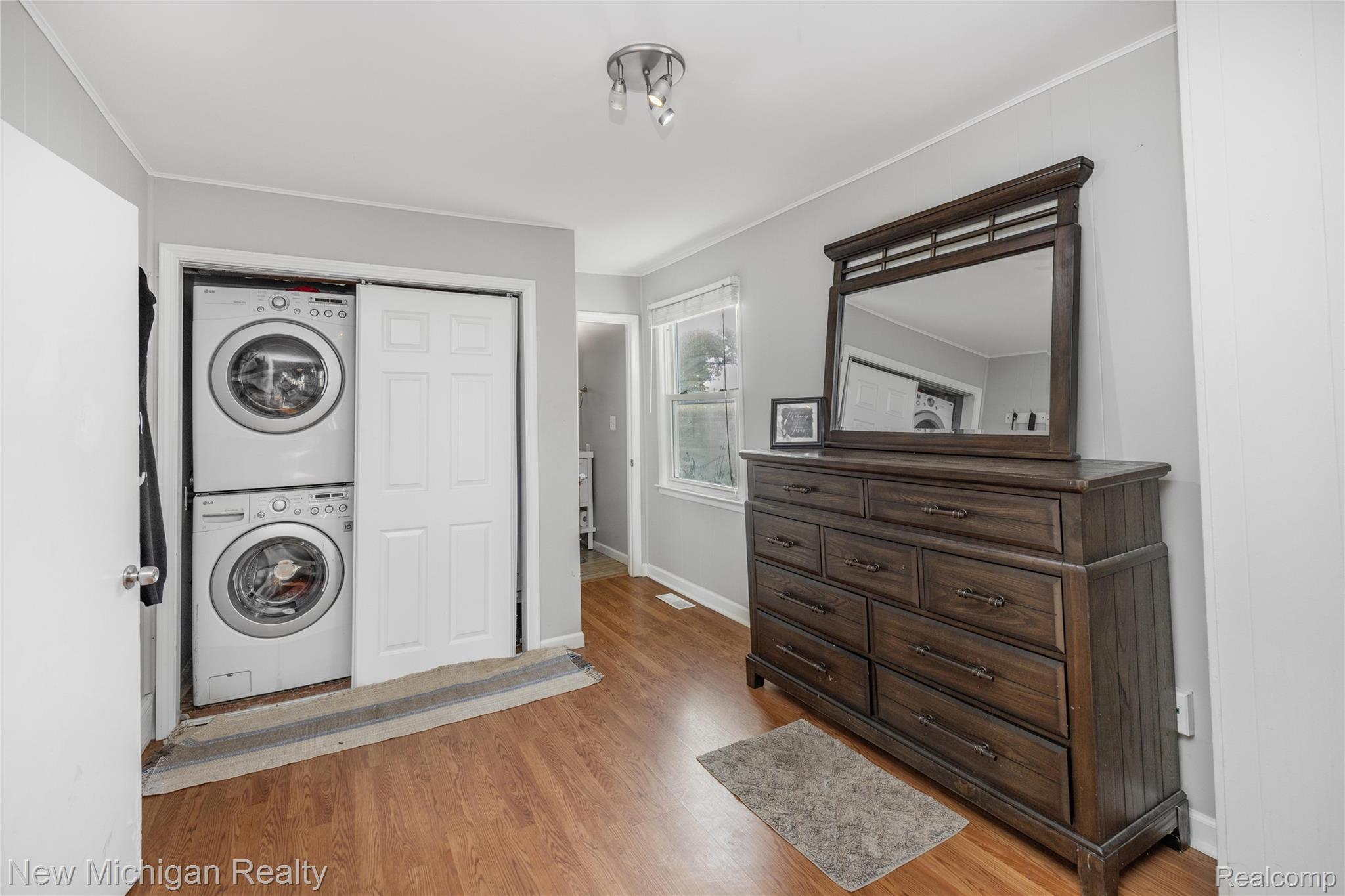 8665 Cooley Lake Road Commerce Township, MI 48382 - Photo 31 of 52 Laundry area with light wood finished floors, stacked washer / dryer, and ornamental molding