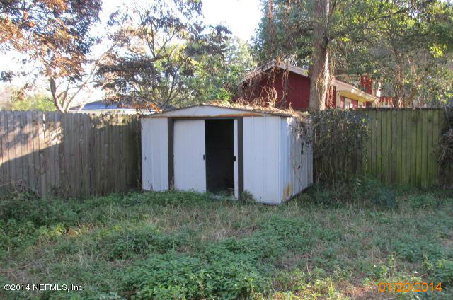 5213 Sunderland Road Jacksonville, FL 32210 - Photo 4 of 6 a view of a small yard with large tree and wooden fence