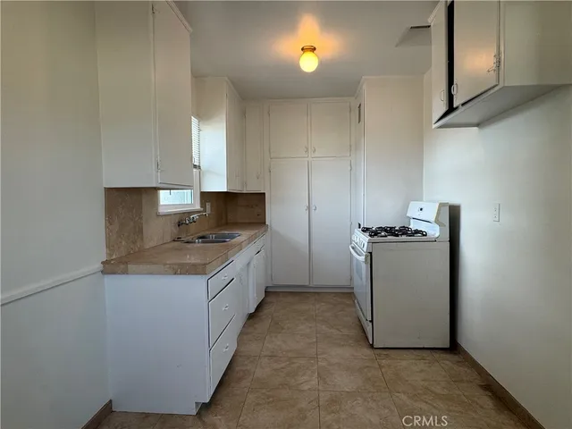a kitchen with a sink a stove cabinets and a window