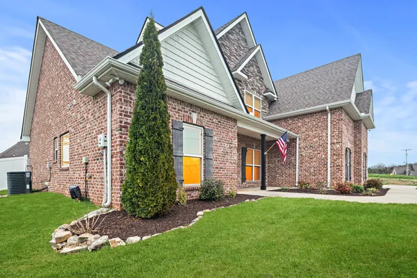 a view of a house with a big yard and large trees