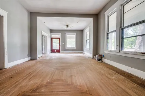 a view of an empty room with a window and wooden floor
