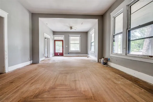 a view of an empty room with a window and wooden floor