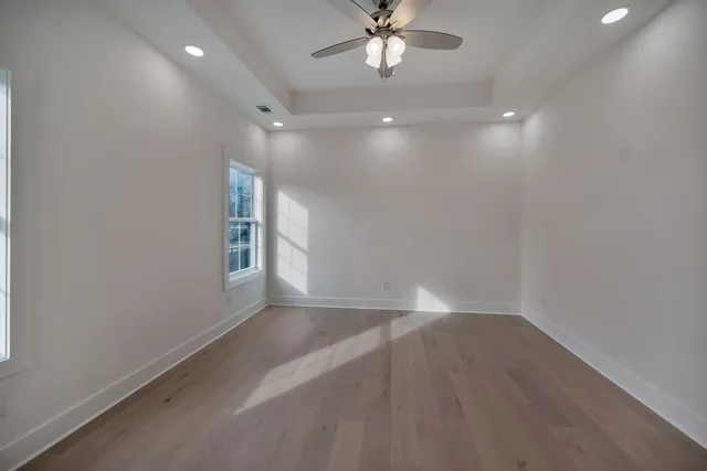 an empty room with wooden floor and windows