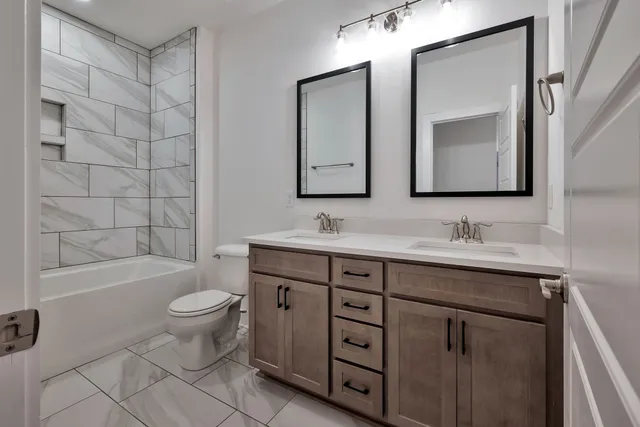 a bathroom with a double vanity sink a toilet and a bathtub