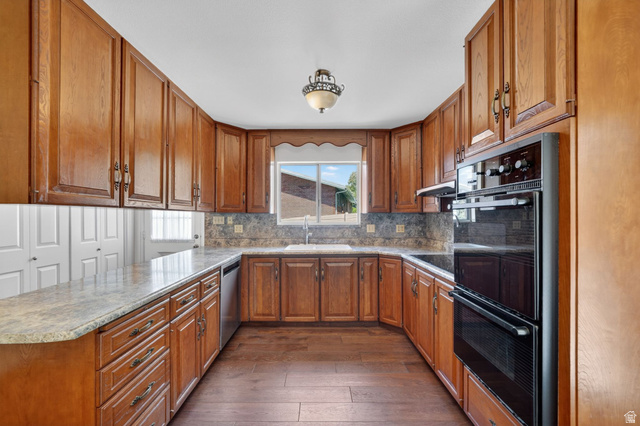 3120 North Apache Way Provo, UT 84604 - Photo 3 of 58 U-shaped kitchen featuring wood cabinetry, light-toned countertops, and a tile backsplash