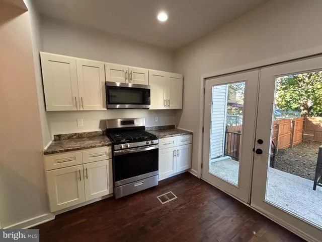 a kitchen with granite countertop a stove and a wooden floor