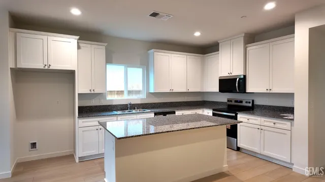 a kitchen with granite countertop a sink cabinets and stainless steel appliances
