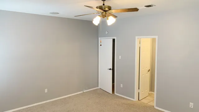 an empty room with a ceiling fan and a window