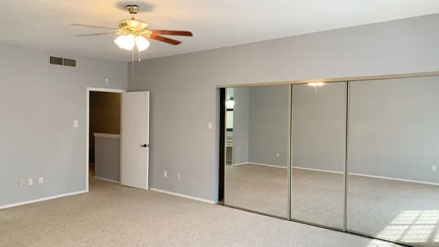 a view of an empty room with a fan and a window
