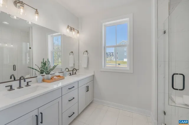 a bathroom with a double vanity sink mirror and next to a window