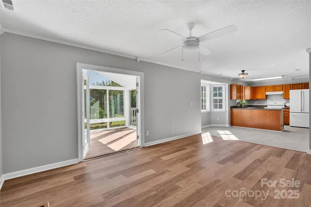 a view of a livingroom with wooden floor and a kitchen