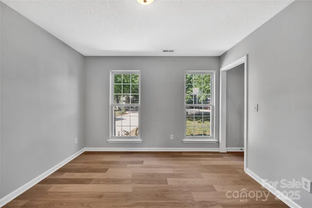 a view of an empty room with wooden floor and window