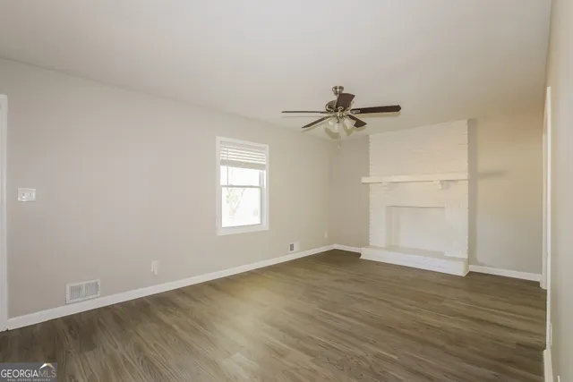 an empty room with wooden floor fan and windows