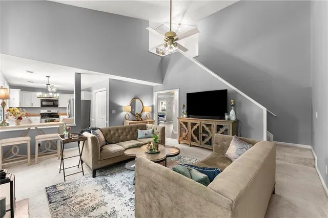 a living room with furniture a flat screen tv and kitchen view