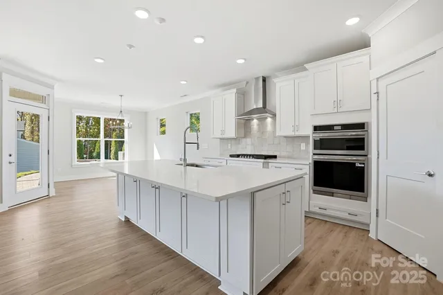 a large kitchen with stainless steel appliances kitchen island granite countertop a stove and a refrigerator