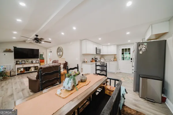 a kitchen with stainless steel appliances granite countertop a refrigerator stove top oven dining table and chairs