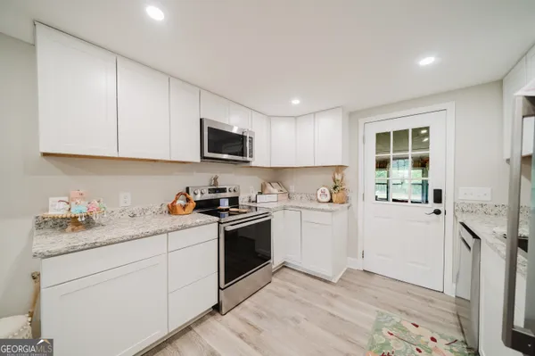 a kitchen with granite countertop white cabinets and white appliances