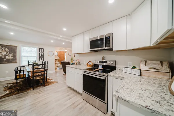 a kitchen with stainless steel appliances granite countertop a stove top oven a sink a dining table and chairs with wooden floor