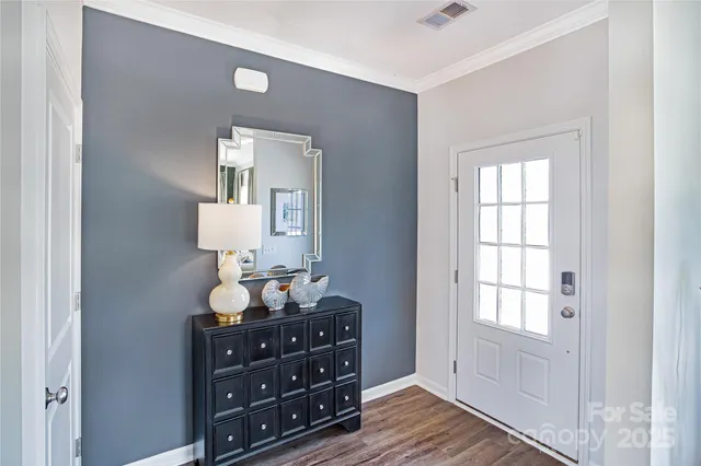 a room with wooden floor with lamp on dresser and a window