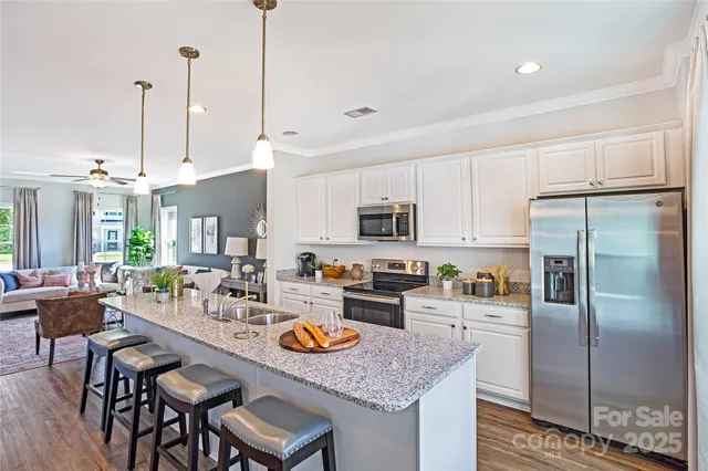 a kitchen with a refrigerator a stove a kitchen island with a dining table and chairs