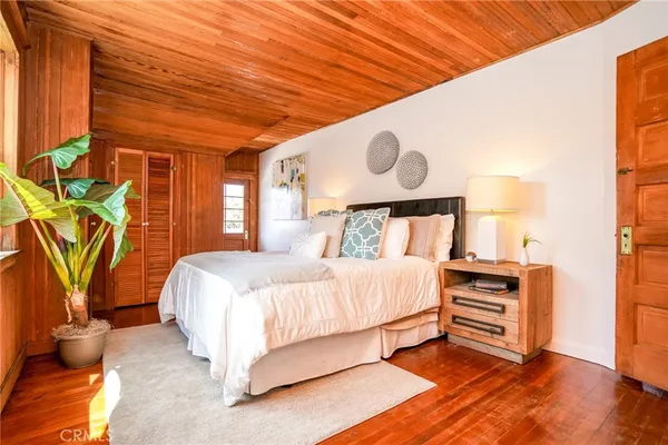 a bedroom with a bed and dresser with wooden floor