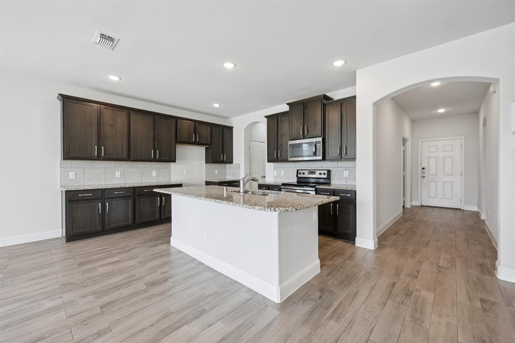 1205 Templin Avenue Forney, TX 75126 - Photo 6 of 40 a kitchen with kitchen island granite countertop wooden floors stainless steel appliances and cabinets