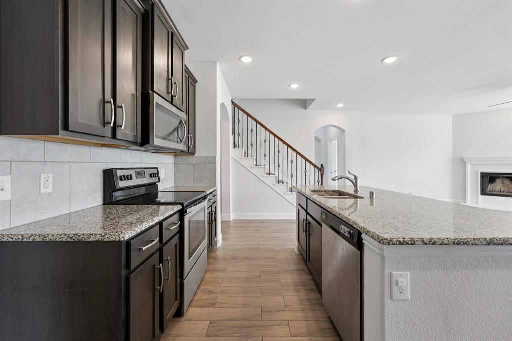 1205 Templin Avenue Forney, TX 75126 - Photo 8 of 40 a kitchen with granite countertop a sink a stove and cabinets