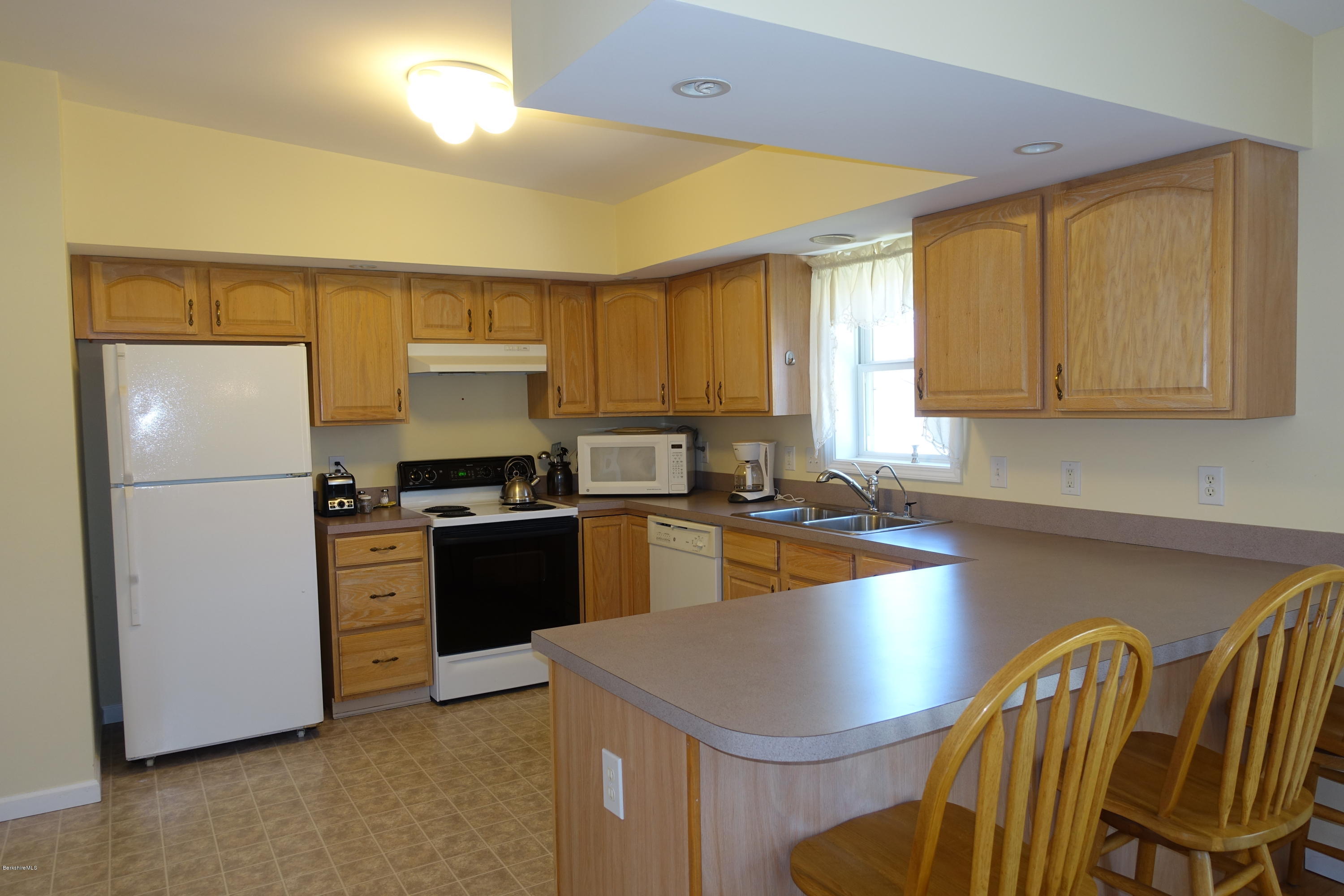 1254 Main Road Stamford, VT 05352 - Photo 21 of 39 a kitchen with stainless steel appliances granite countertop a refrigerator a sink a stove a dining table and chairs with wooden floor