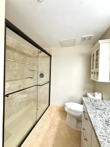 a bathroom with a granite countertop sink a toilet and shower