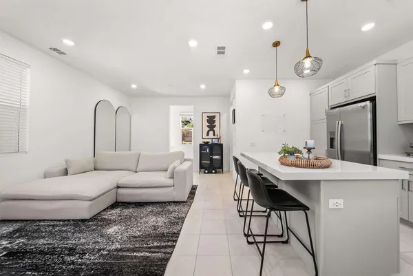 a living room with furniture a table and kitchen view