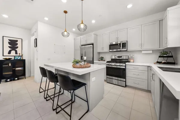 a kitchen with stainless steel appliances a stove a sink a oven a kitchen island with chairs and cabinets