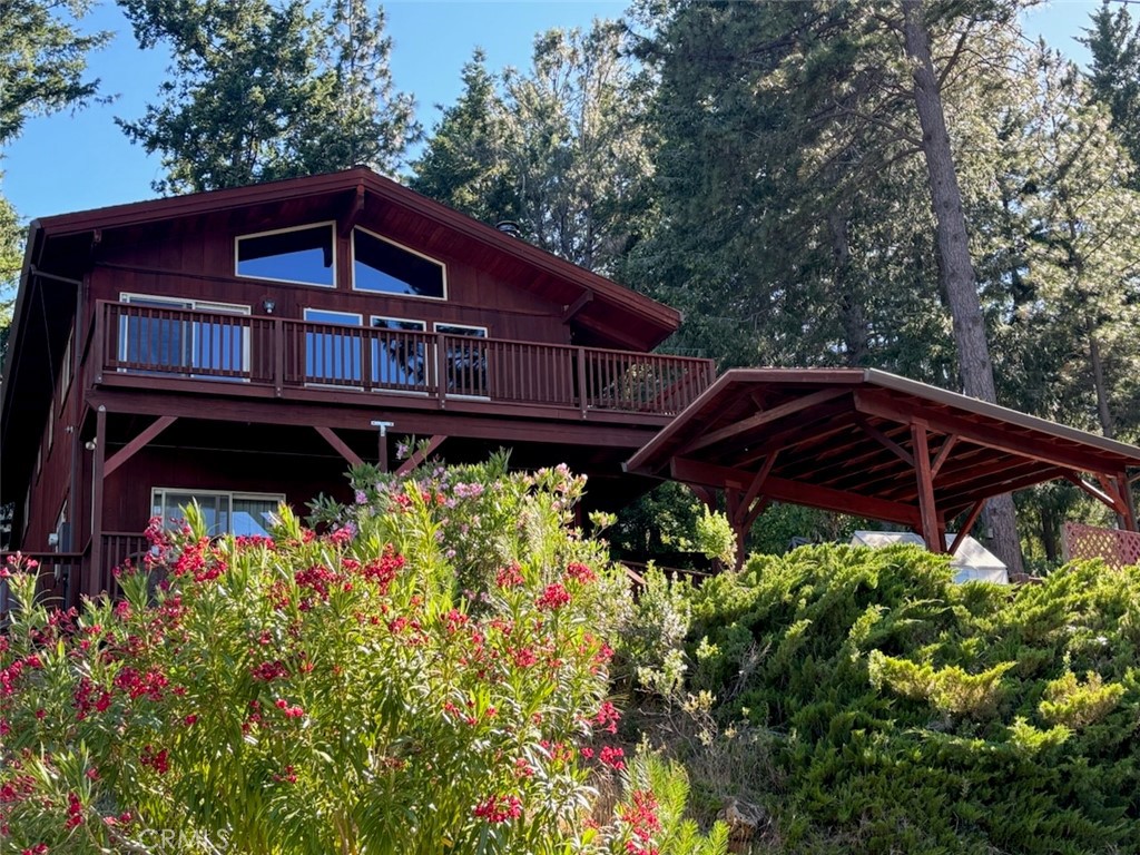 a view of a small house with a big yard and large trees