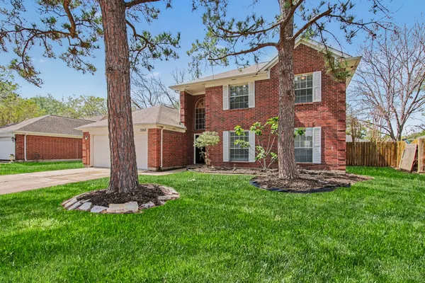 a front view of a house with a garden and trees